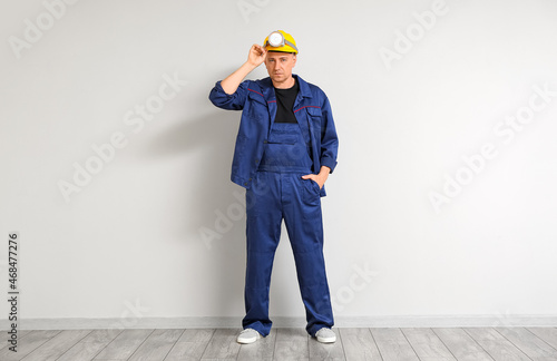 Mature worker with headlamp flashlight near light wall