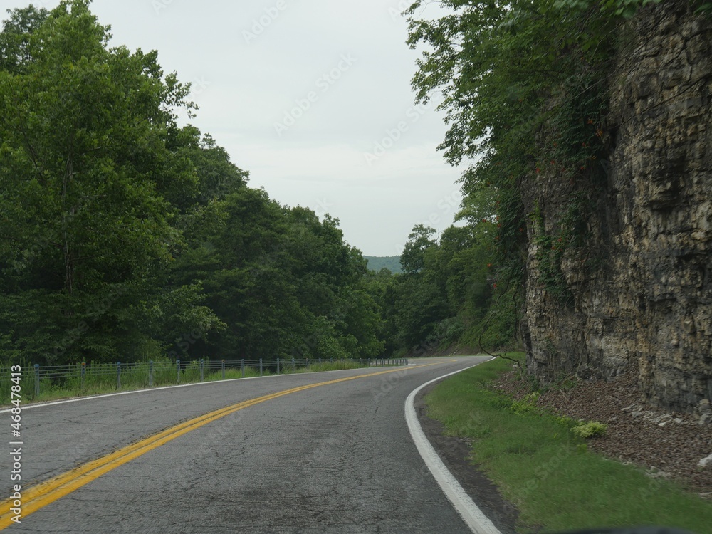 Winding asphalt road with rock walls on one side