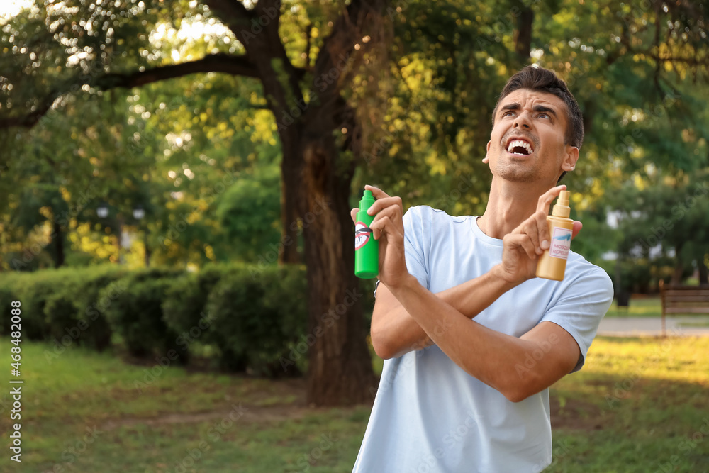 Young man with mosquito repellents outdoors Young man with mosquito repellents outdoors