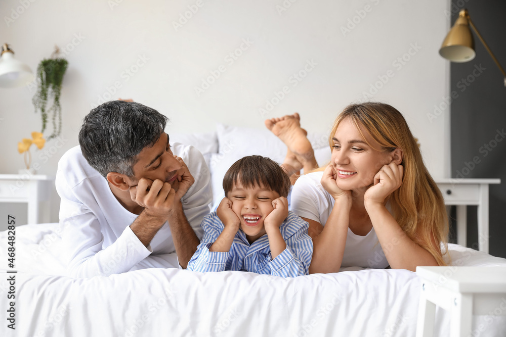 Happy parents with their little son lying on bed Happy parents with their little son lying on bed