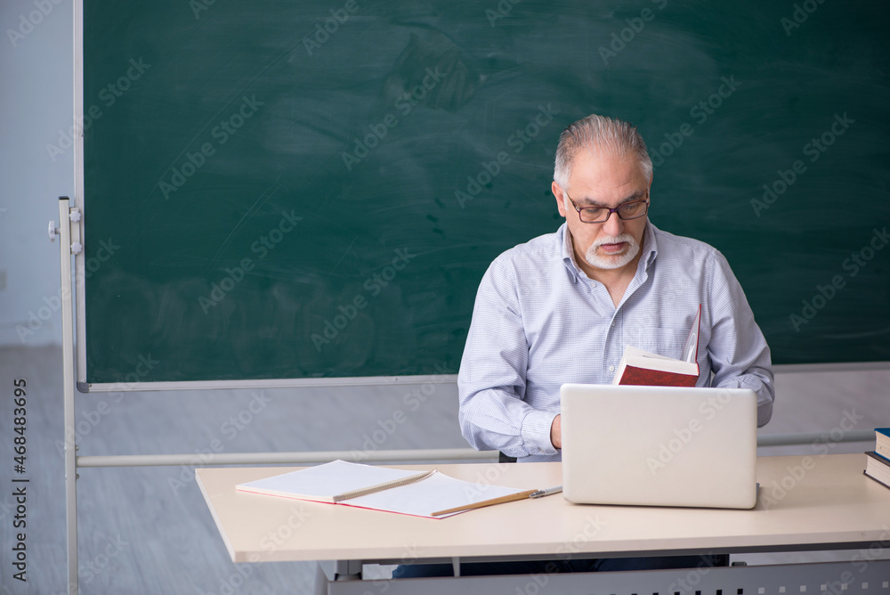 Old male teacher in front of green board Old male teacher in front of green board