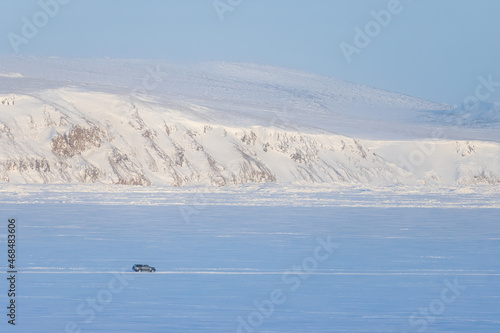 Winter Arctic landscape. The car is driving on snow and ice. Winter ice road along the frozen river. Extreme travel and car trips in the Arctic. Anadyr estuary, Chukotka, Siberia, Far North of Russia.
