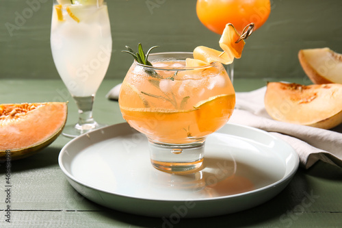 Glass of cold melon cocktail on color wooden background