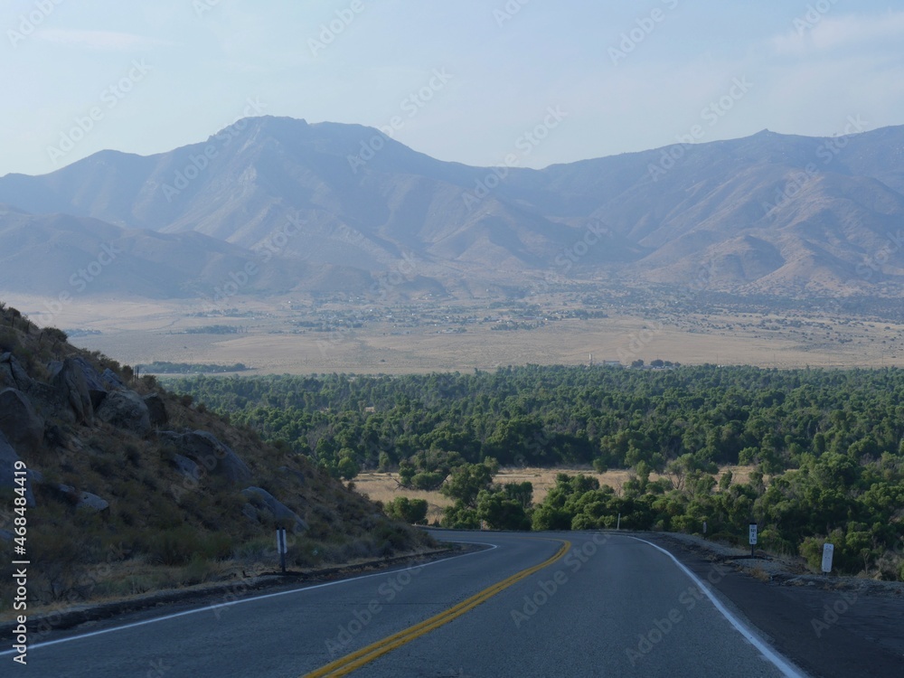 Winding sloping road with distant mountains in the background, Kern County, California.
