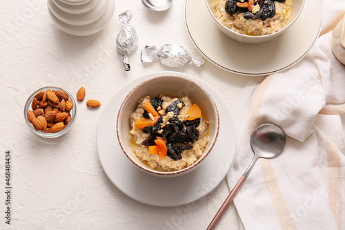 Fototapeta Naklejka Na Ścianę i Meble -  Delicious oatmeal with prunes, dried apricots and almond nuts in bowls on light table