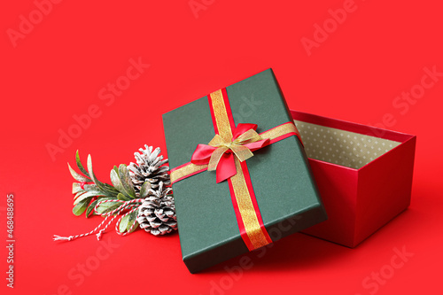 Opened gift box and Christmas decor on red background © Pixel-Shot