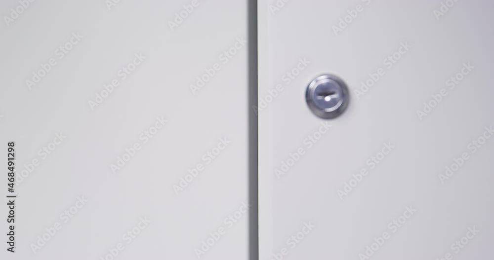 Dodgy student tries to open grey metal door OF school locker with lock from inside using long aluminum ruler extreme closeup Dodgy student tries to open grey metal door OF school locker with lock from inside using long aluminum ruler extreme closeup