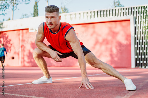 sports man in a red t-shirt on the sports ground doing exercises