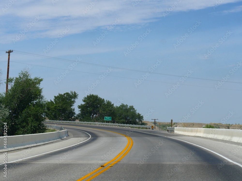 Winding road over a bridge with a sign to the Bentonite Plants in Wyoming