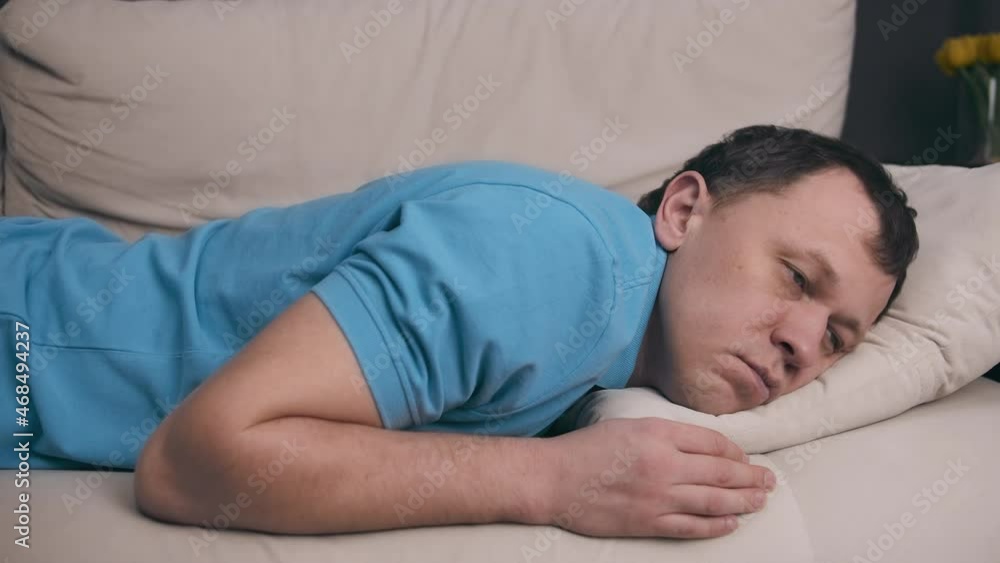 A man in a blue T-shirt collapses on the couch after a hard day A man in a blue T-shirt collapses on the couch after a hard day
