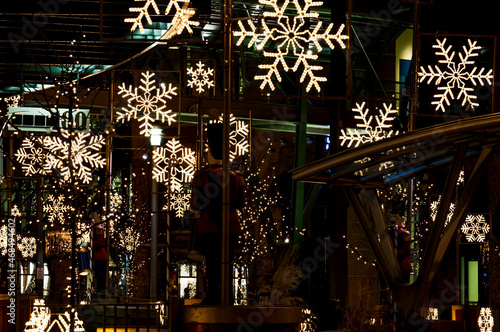 Urban downtown snowflake Christmas decorations lit up and seen on street level outside at night..