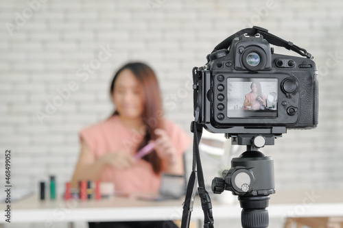 Asian young attractive woman beauty blogger happy talking and review cosmetic product while recording camera live stream online to audience from home. Selective focus.