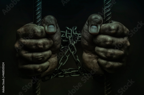 closeup of hand in jail, hands on a black background, a prisoner behind bars, trapped
