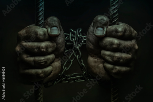 closeup of hand in jail, hands on a black background, a prisoner behind bars, trapped photo