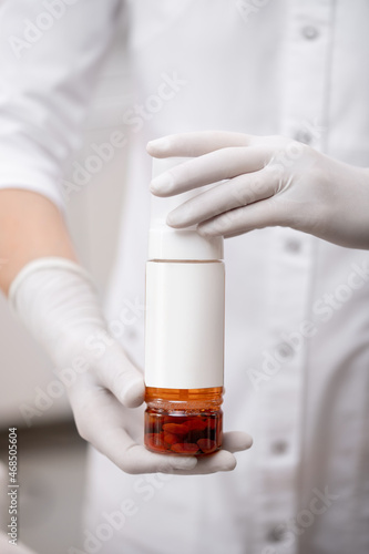 Facial skin care product in bottle dispenser with injection in hands of doctor with gloves