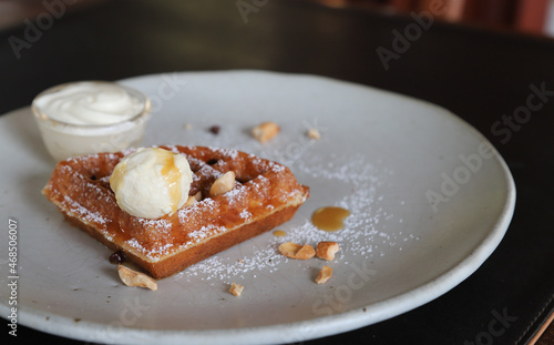 Closeup of ice cream with honey on a piece of waffle on white ceremic plate. photo