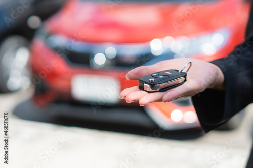 Sale agent car holding car keys with car on background,rent car and car insurance concept.