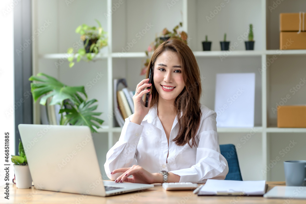 Beautiful young Asian businesswoman charming smiling and talking on the mobile phone in the office.. Beautiful young Asian businesswoman charming smiling and talking on the mobile phone in the office..