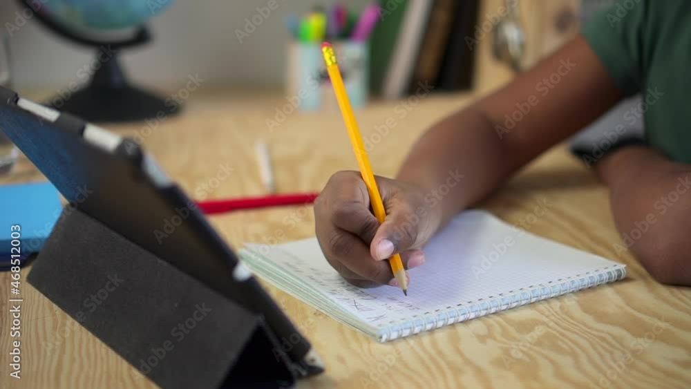 Remote education of junior kids. Little black child student writes with