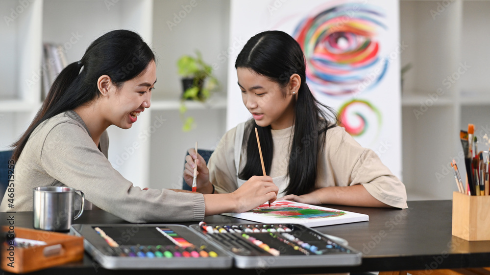 Fototapeta premium Asian girl having fun painting with teacher in art class.