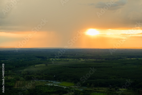 Distant Rainfall in front of the sunset view from wooden bridge on cliff, viewpoint of Wat Phu Thok temple at Bueng Kan province amazing Thailand. © Tanongsak