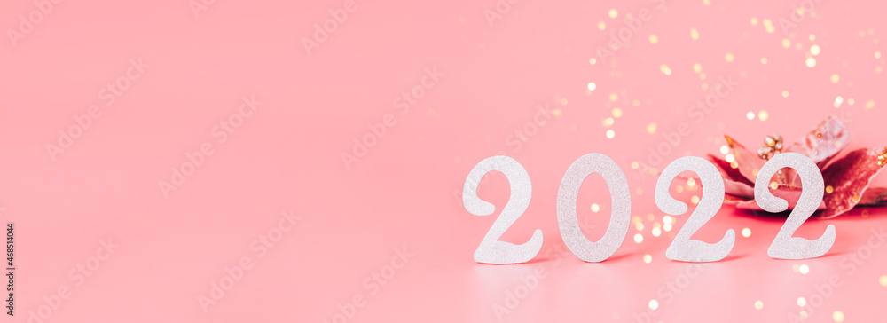 Festive composition of numbers 2022 New Year's toys pink pastel background. New year 2022, banner greeting card layout