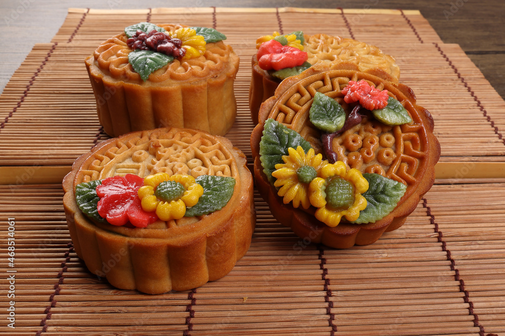 Colourful flower decorated mooncake Chinese mid autumn festival on bamboo food mat background