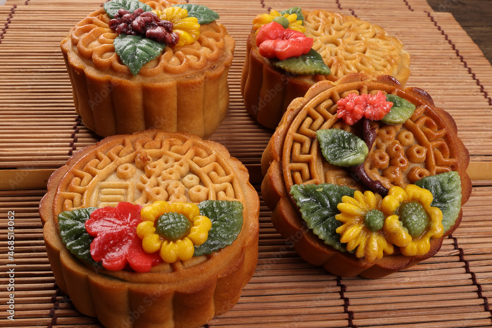 Colorful flower decorated mooncake Chinese mid autumn festival on bamboo food mat background
