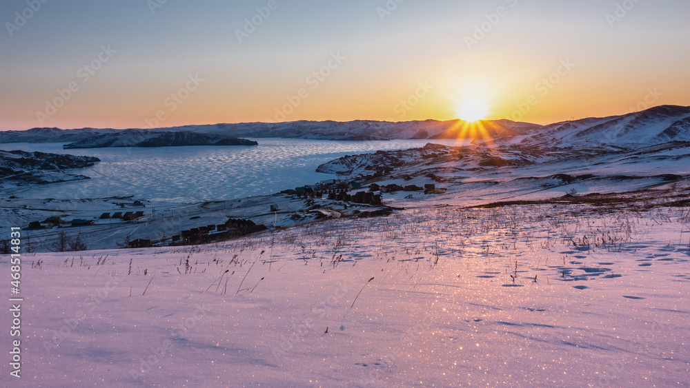 Winter dawn in Siberia. The rays of the rising sun illuminate the mountains, the frozen lake. The sky is highlighted in orange. The snow sparkles. Morning golden hour. Baikal Winter dawn in Siberia. The rays of the rising sun illuminate the mountains, the frozen lake. The sky is highlighted in orange. The snow sparkles. Morning golden hour. Baikal