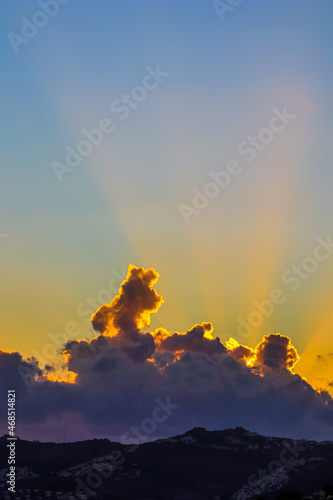 Background from a beautiful sunset with clouds and sunlights over mountanous coast. High quality photo