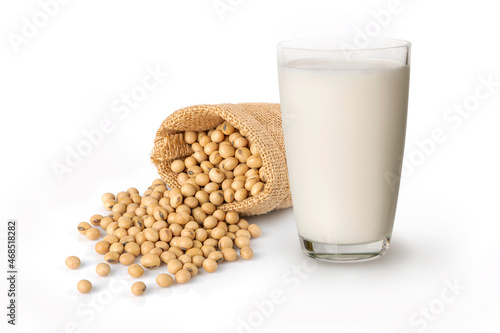 Glass of soymilk with soybeans in bag on white background.