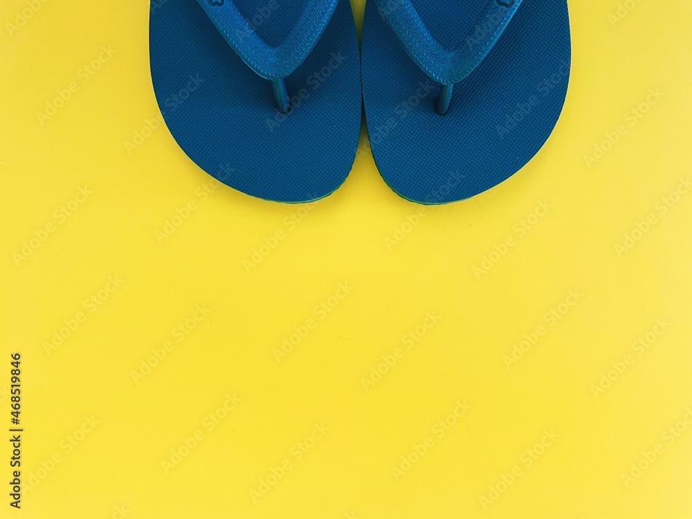 blue flip flops on yellow background 