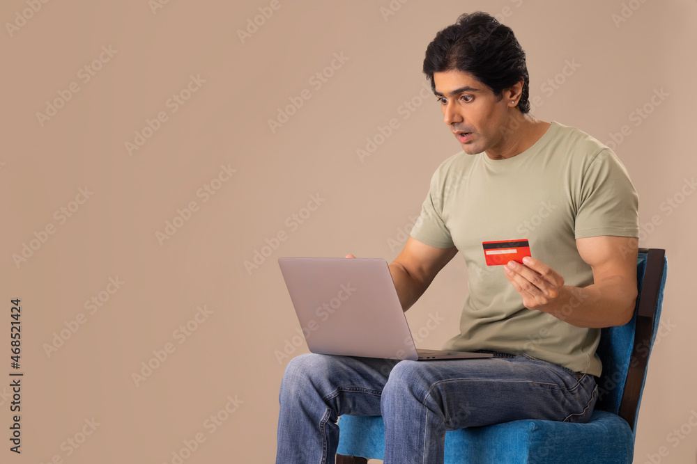 Indian man shopping online through laptop using credit card Indian man shopping online through laptop using credit card