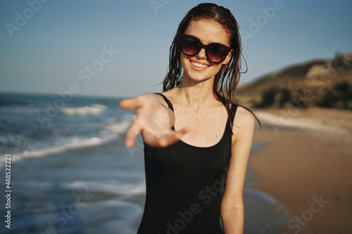 cheerful woman in a black swimsuit walking along the beach tropics summer