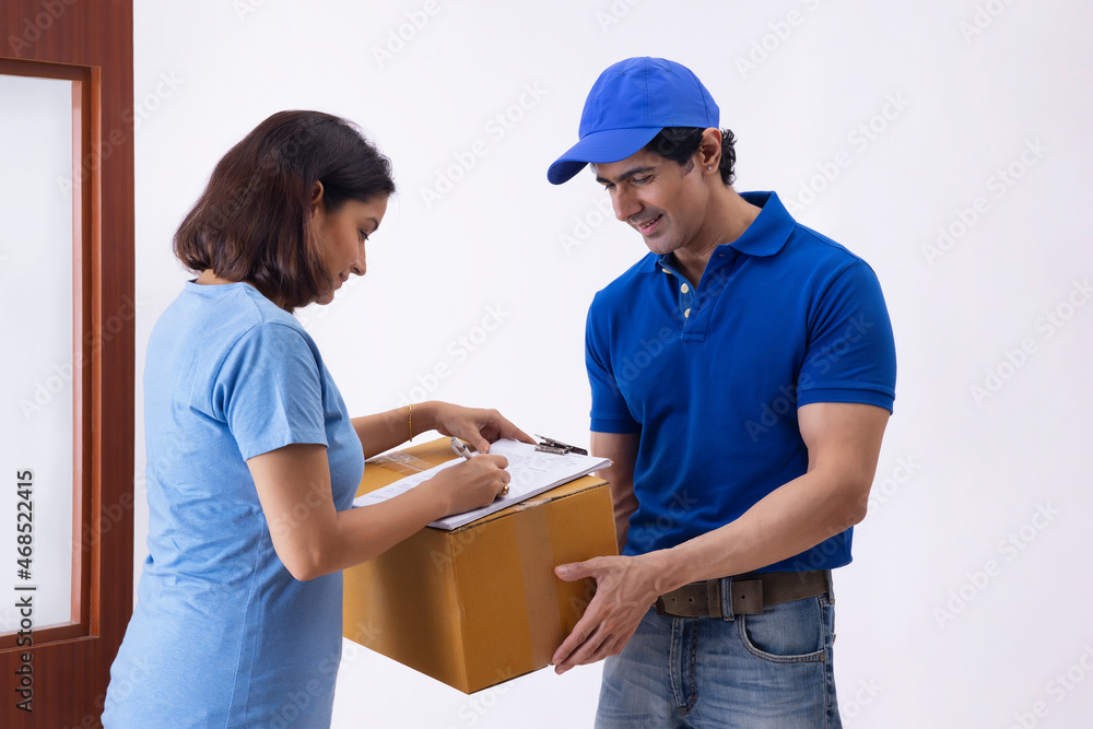 Smart Indian woman signing a home delivery receipt of a package at the time of delivery Smart Indian woman signing a home delivery receipt of a package at the time of delivery