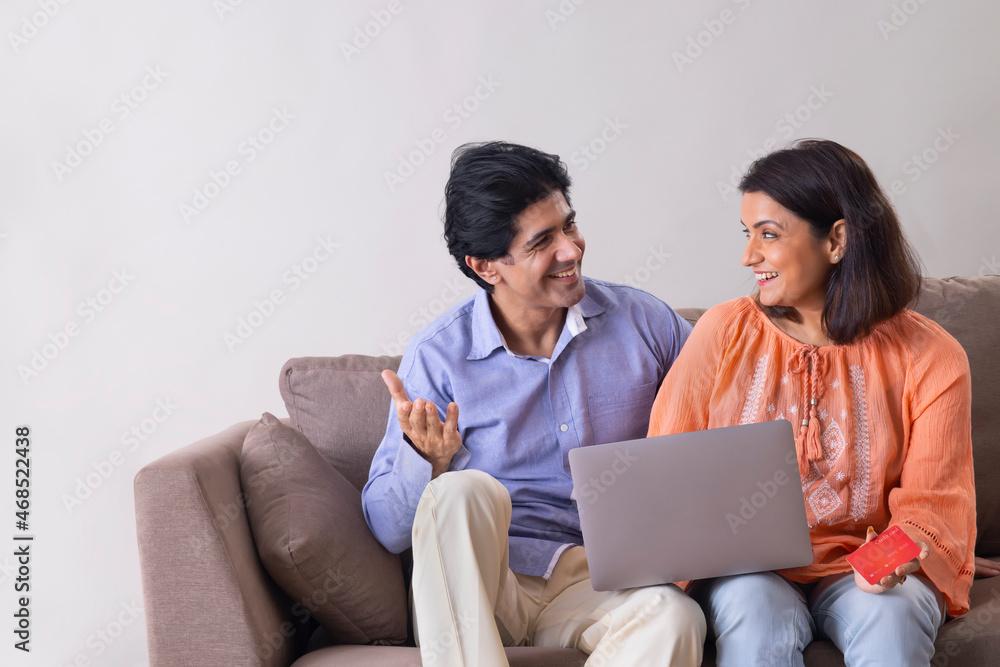 Indian middle age couple shopping online through laptop using credit card Indian middle age couple shopping online through laptop using credit card