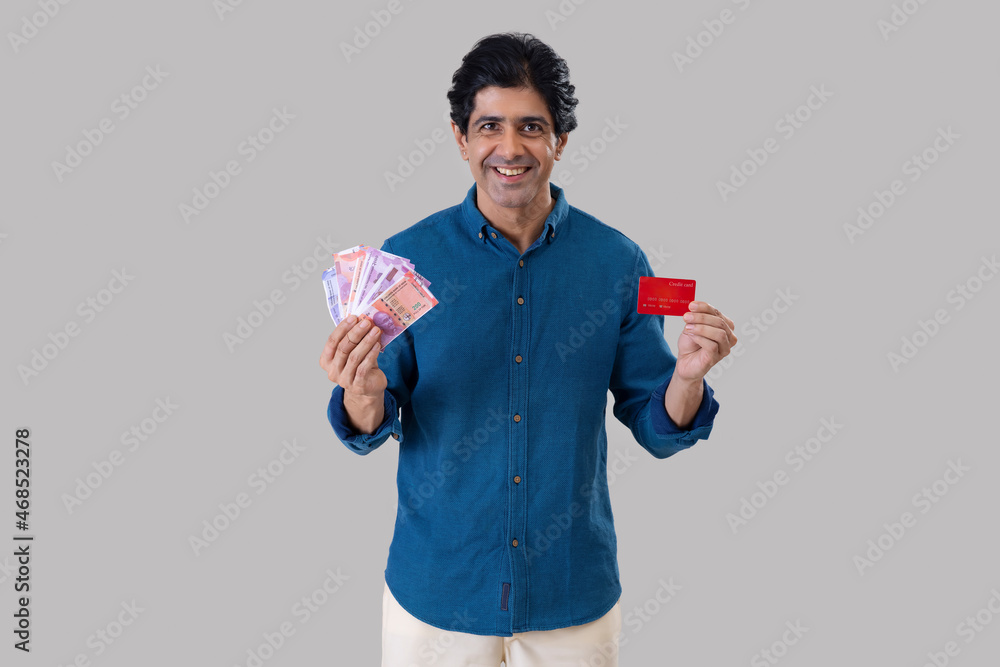 Indian man standing in front of camera with holding a credit card and Indian currency Indian man standing in front of camera with holding a credit card and Indian currency