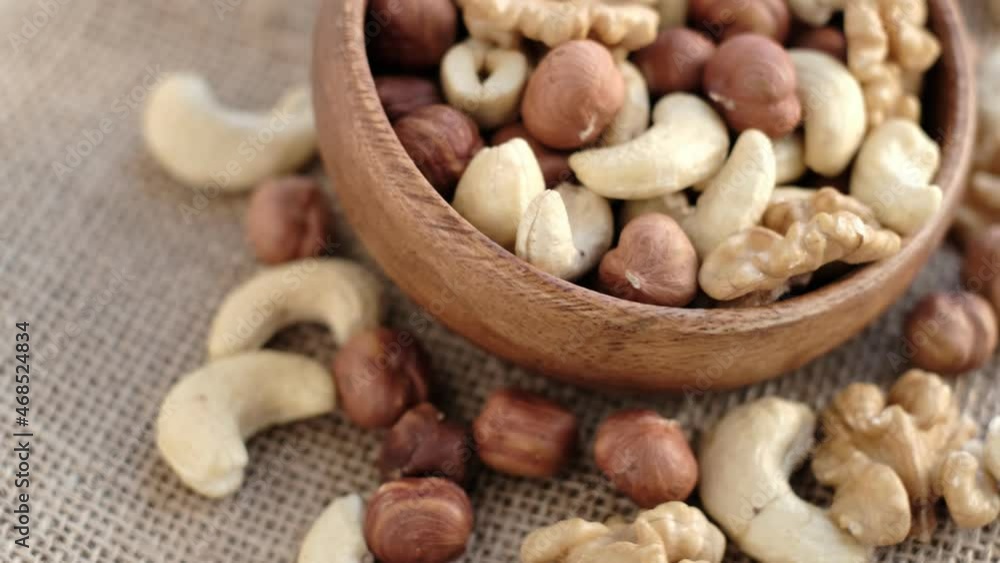 mixed nuts in a wooden cup against the background of fabric from burlap. Walnut, hazelnuts and cashews. Wood bowl with different tasty nuts mixed nuts in a wooden cup against the background of fabric from burlap. Walnut, hazelnuts and cashews. Wood bowl with different tasty nuts