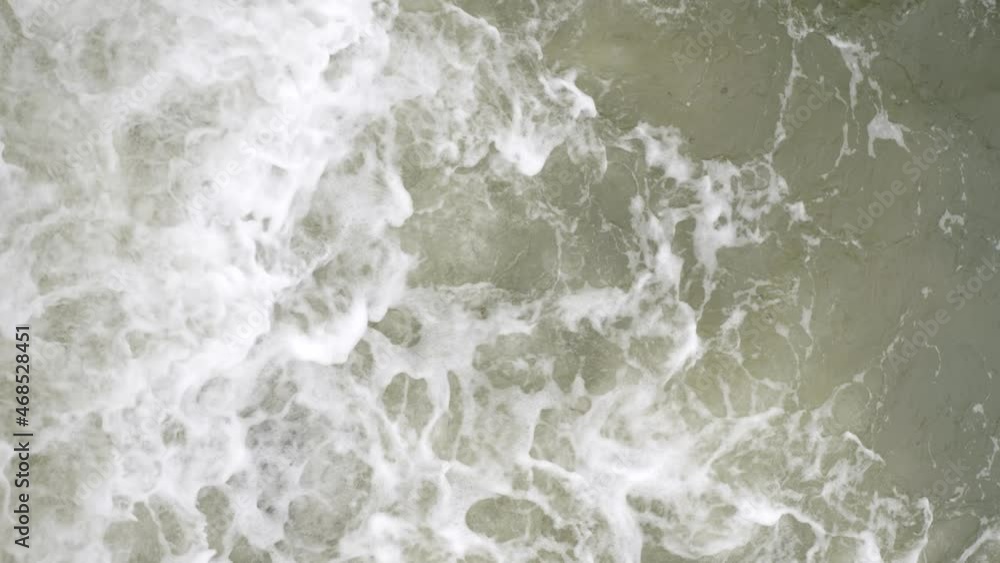 Top view of the sea waves that beat against rocks on cloudy day. Vertical video and slow motion Top view of the sea waves that beat against rocks on cloudy day. Vertical video and slow motion