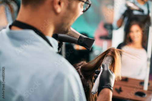 Close-up of hairdresser styling woman's hair at the salon.