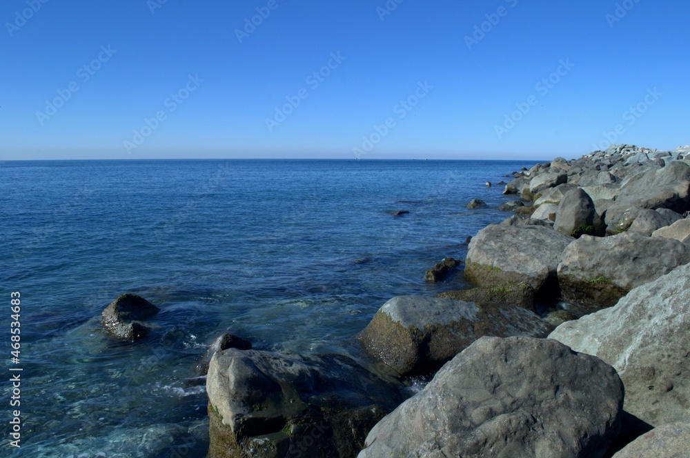 Blue sea and sky. There is a stone bank on the side. The Black Sea