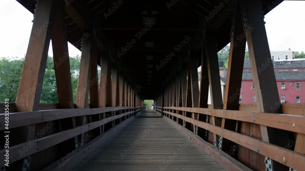 A still interior shot of a beautiful covered bridge with trees and buildings visible through the sides creating a sense of perspective. A still interior shot of a beautiful covered bridge with trees and buildings visible through the sides creating a sense of perspective.
