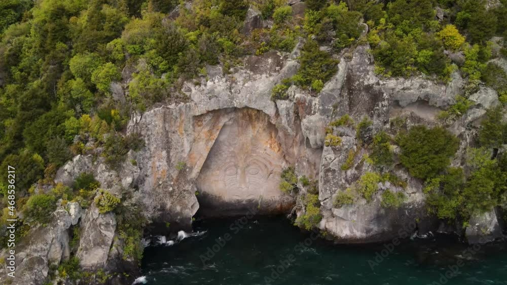 Maori mask carving, artwork in New Zealand. Spectacular sculpture carved to rocky cliff, Lake Taupo - Aerial tilt down Maori mask carving, artwork in New Zealand. Spectacular sculpture carved to rocky cliff, Lake Taupo - Aerial tilt down