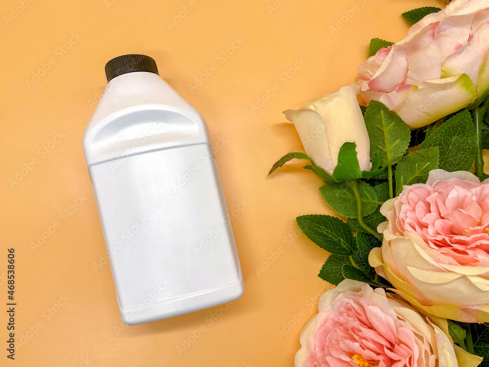 Advertising of funds on a beautiful beige background with peonies. A white bottle for cosmetics or antiseptic. Advertising of funds on a beautiful beige background with peonies. A white bottle for cosmetics or antiseptic.