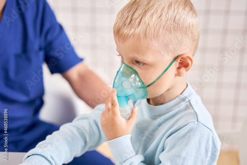 A pediatrician diagnoses lung disease and provides treatment. Breathe the medicine through a nebulizer inhaler.. Portrait of adorable little boy visiting doctor.