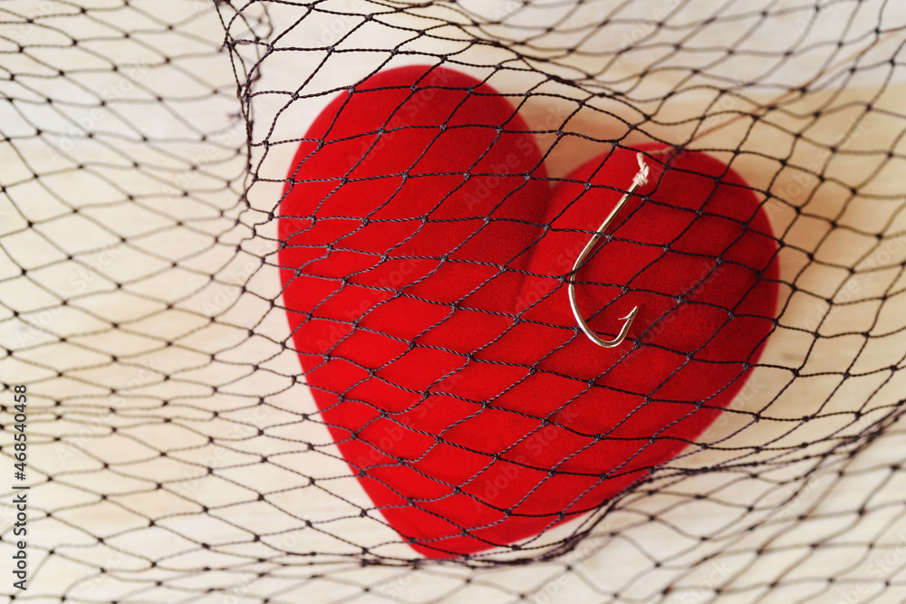 Heart with fish hook in fishing net - Love and freedom concept - obrazy, fototapety, plakaty 