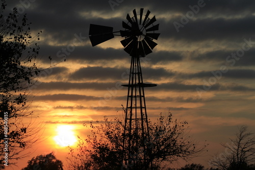 windmill at sunset with Strato Cumulus Clouds north of Hutchinson Kansas USA out in the country.