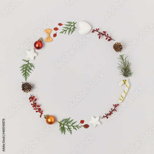Round natural frame or wreath made of christmas ornaments, greens and pine cones.