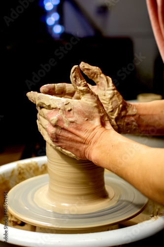 Master class on modeling of clay on a potter's. woman hands form by a clay pot. The potter works in a workshop