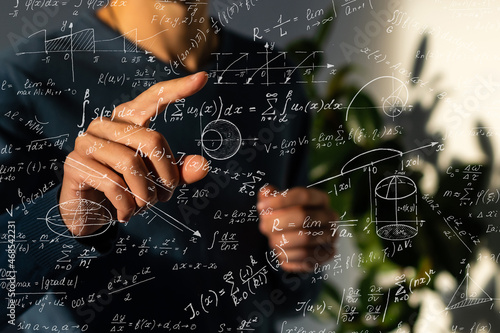 Photos An image of a series of mathematical expressions and a hand pointing a finger at a formula